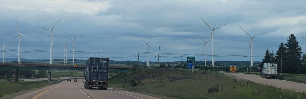 Windfarm along a highway under darkening skies.