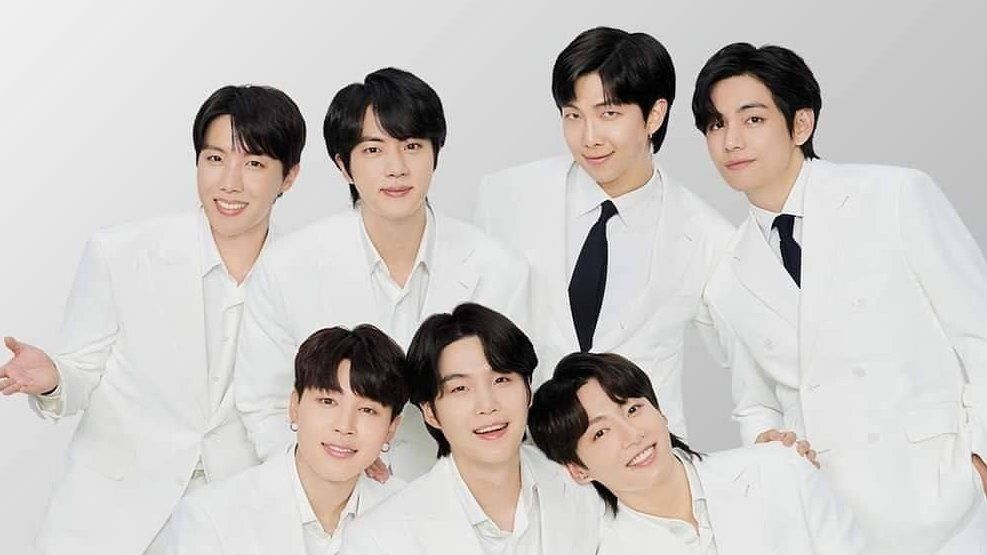 The seven members of BTS, in white suits and dark hair