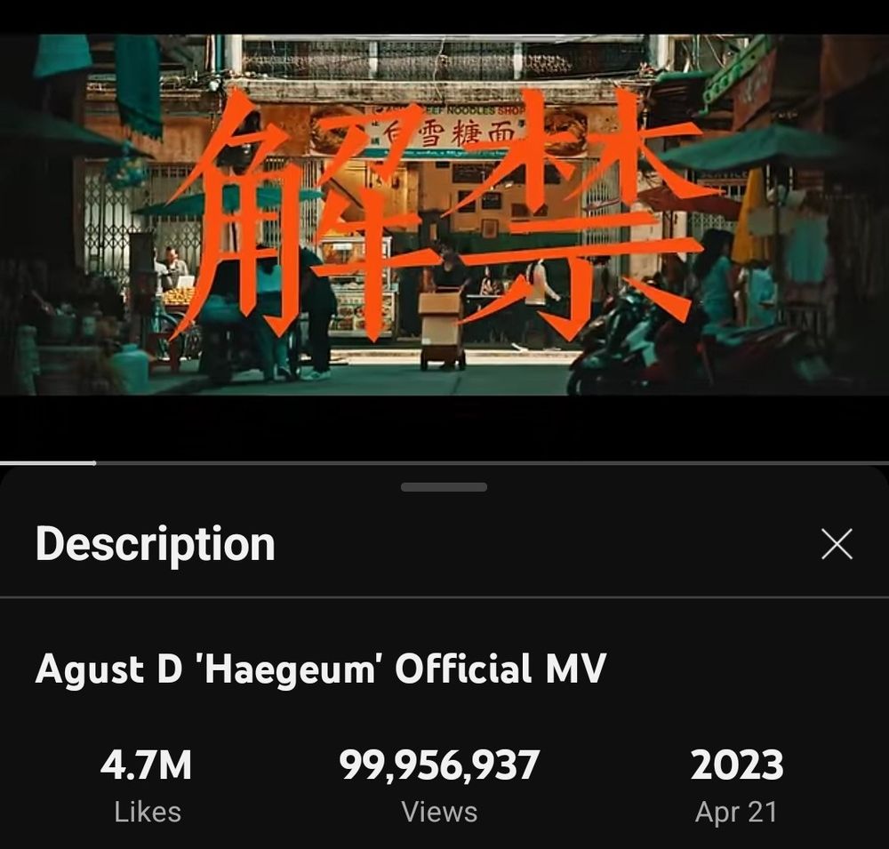 Screenshot from YouTube: the title screen of the MV for the Agust D track Haegeum. Orange Chinese characters against a backdrop of a street in Thailand, partly lit by afternoon sunlight and partly in shadows 