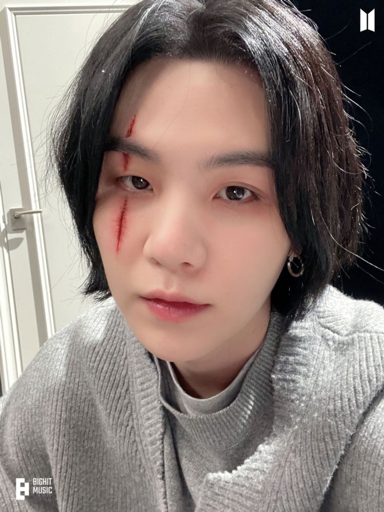 BTS SUGA as Agust D, with dark hair and a prosthetic scar crossing his right eye, from the Amygdala MV behind the scenes