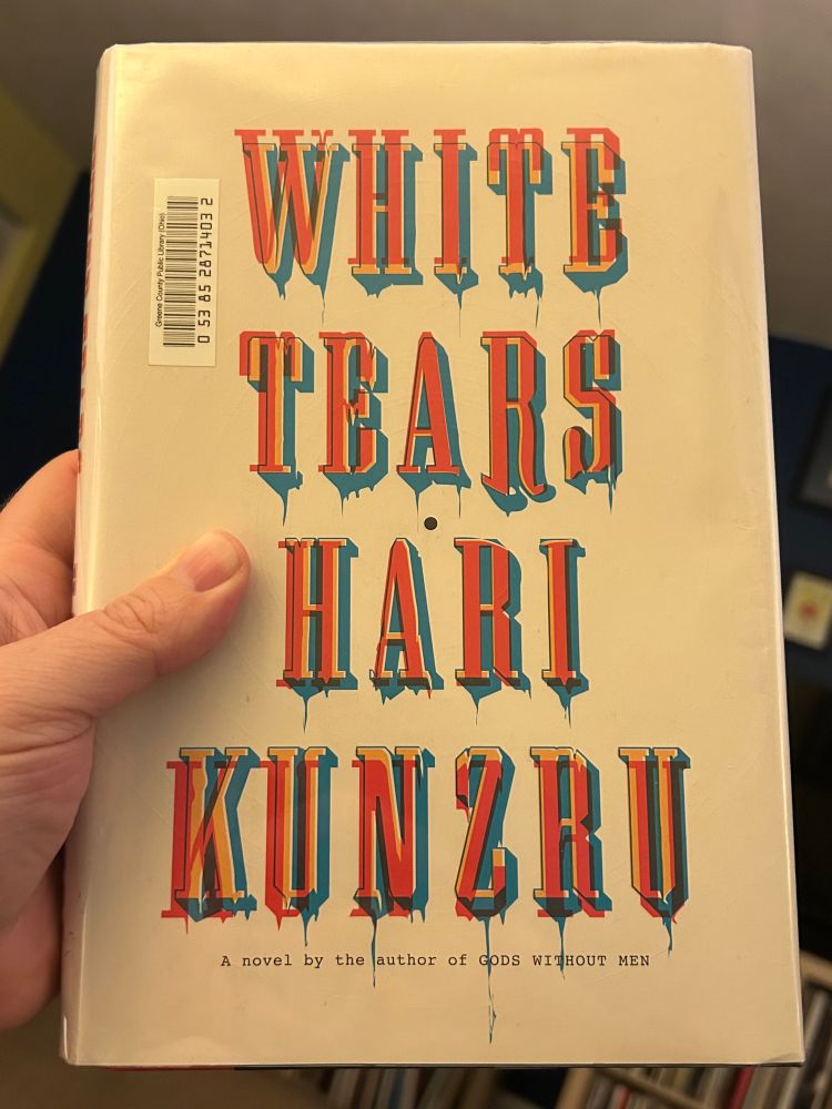 My hand holds a hardcover copy of the book “White Tears” by Hari Kunzru
