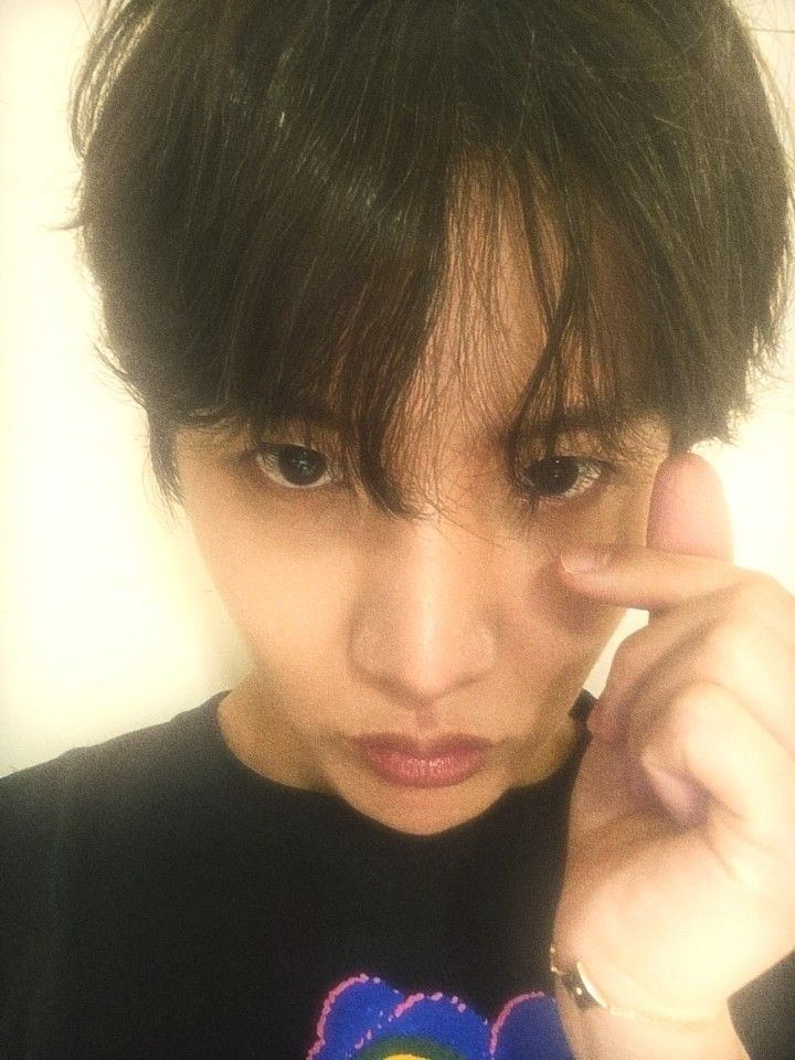a selca of Hobi, he's looking down, lips pursed, giving army a finger heart and staring into our souls with his pretty brown eyes that are slightly covered by his wispy bangs