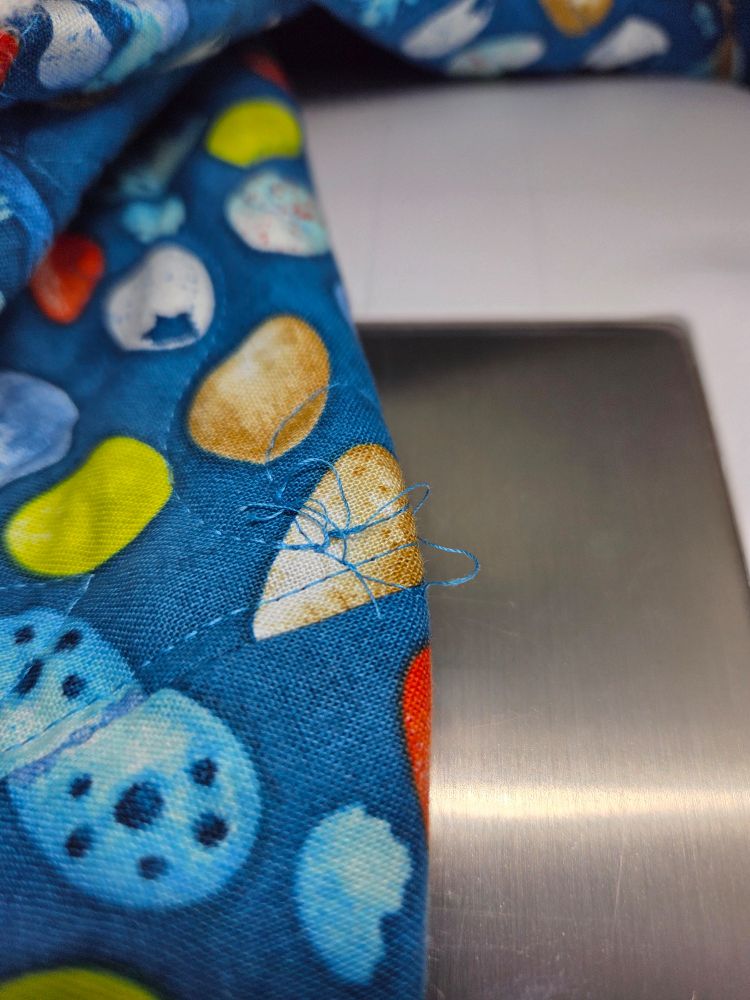 Small nest of threads on the back of a quilt in progress caused by the bobbin running out of thread.