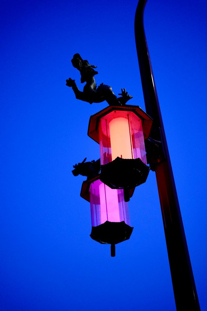 a photo of two colourful street lamps with decorative dragons perched atop