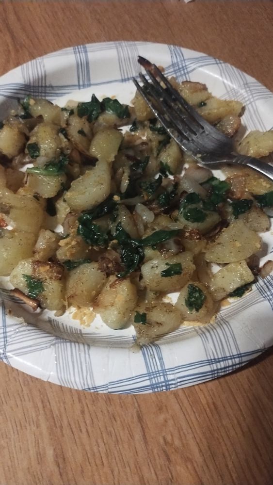 A blue striped white paper plate on a wood counter holds a breakfast and a fork. 