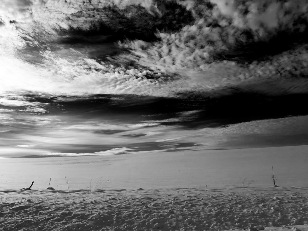 A field of snow under a sky of scattered clouds. 