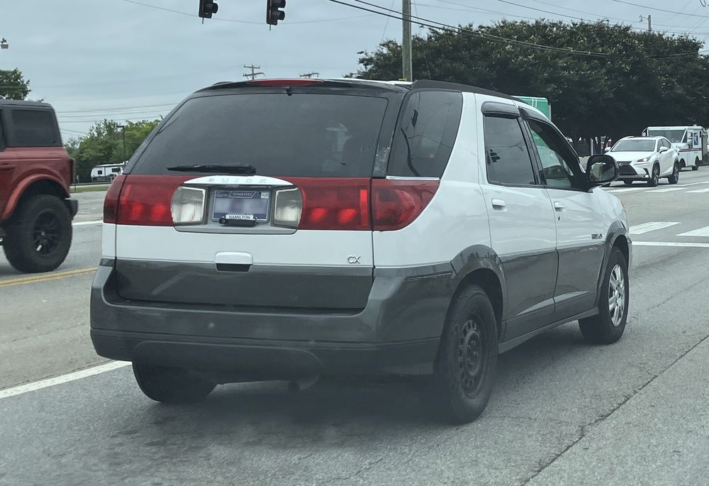 Rear right angle of a white Buick Rendezvous with a missing wheel cover.