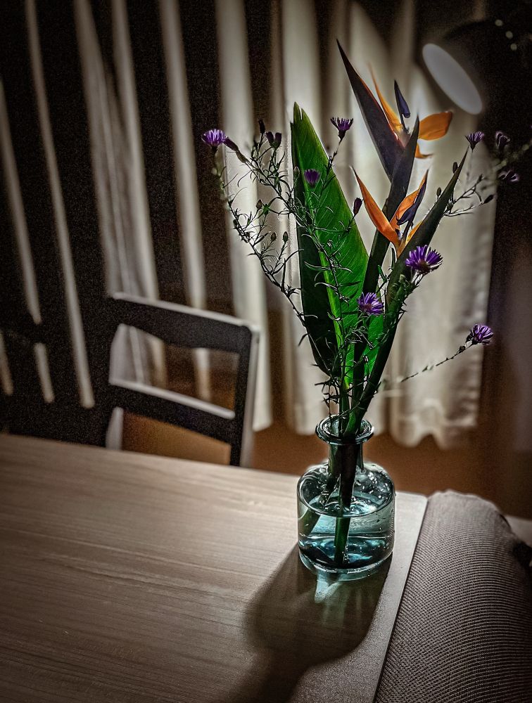 テーブルの上にIKEAの水色の花瓶、かっこいいシルエットの極楽鳥花、背景に間接照明