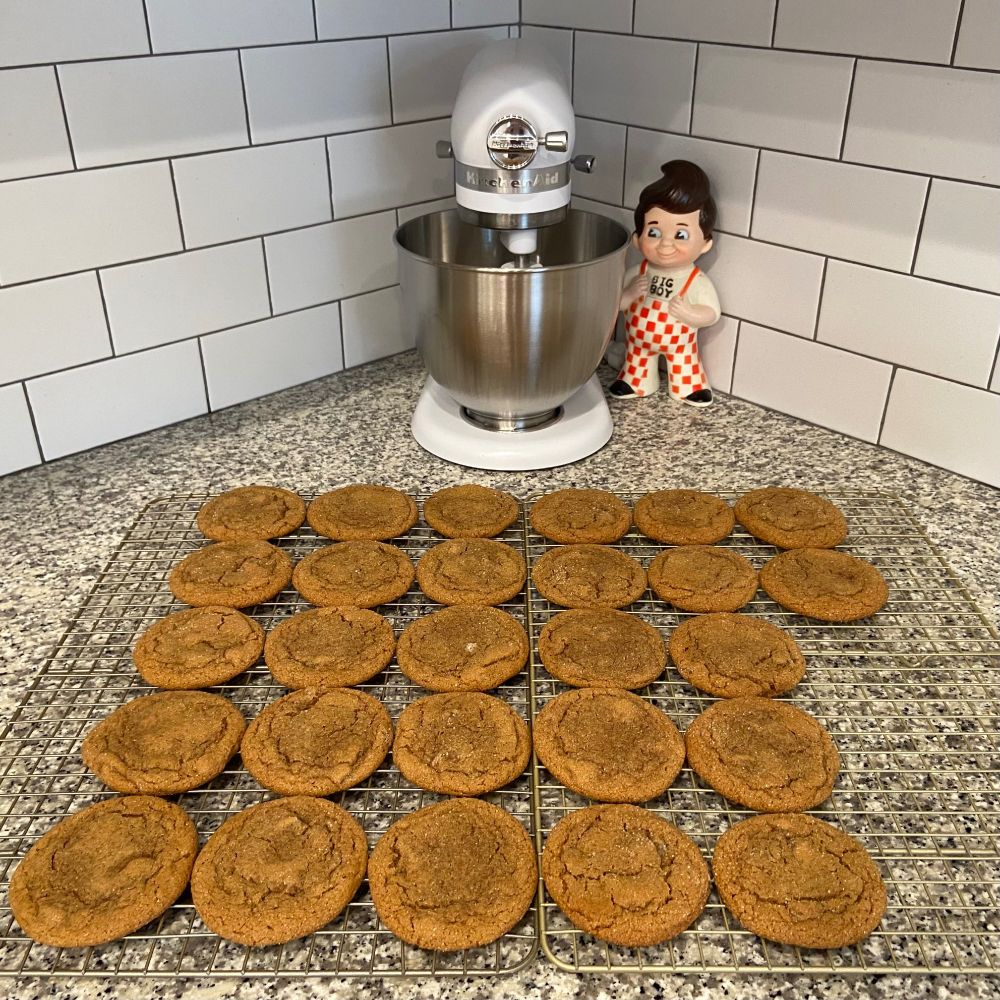 A cooling rack of ginger cookies, a stand mixer, and a Big Boy figurine. 