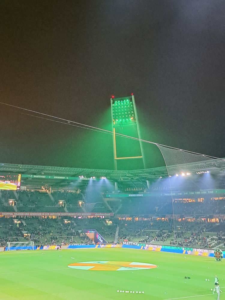 Flutlichtmast. Leuchtet grün
 Stadion füllt sich