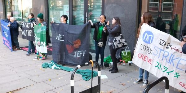 Group of diverse protesters standing on a city sidewalk holding banners with messages supporting Jeff and and the Malvern House strike.
