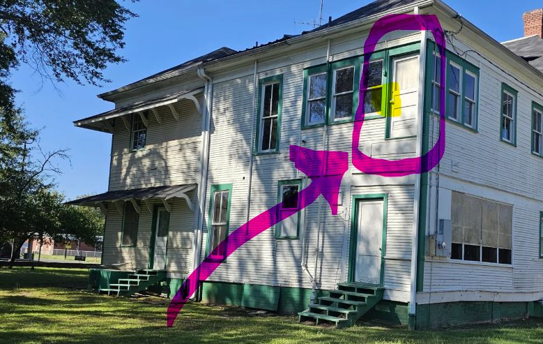 white 2 story home with green trim. door on second story circled in pink. There are no stairs leading down from door to ground.