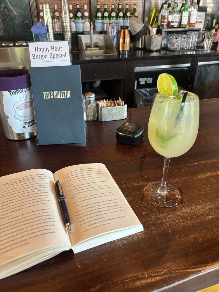 Open book, pen, and alcoholic drink at a bar