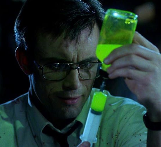 herbert west from the re-animator films drawing a glowing, neon green substance into a syringe