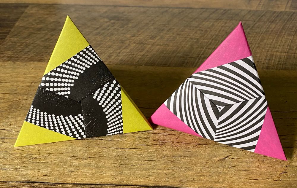 Two origami tetrahedrons with bright solid colors at the corners and black/white patterns the face. 