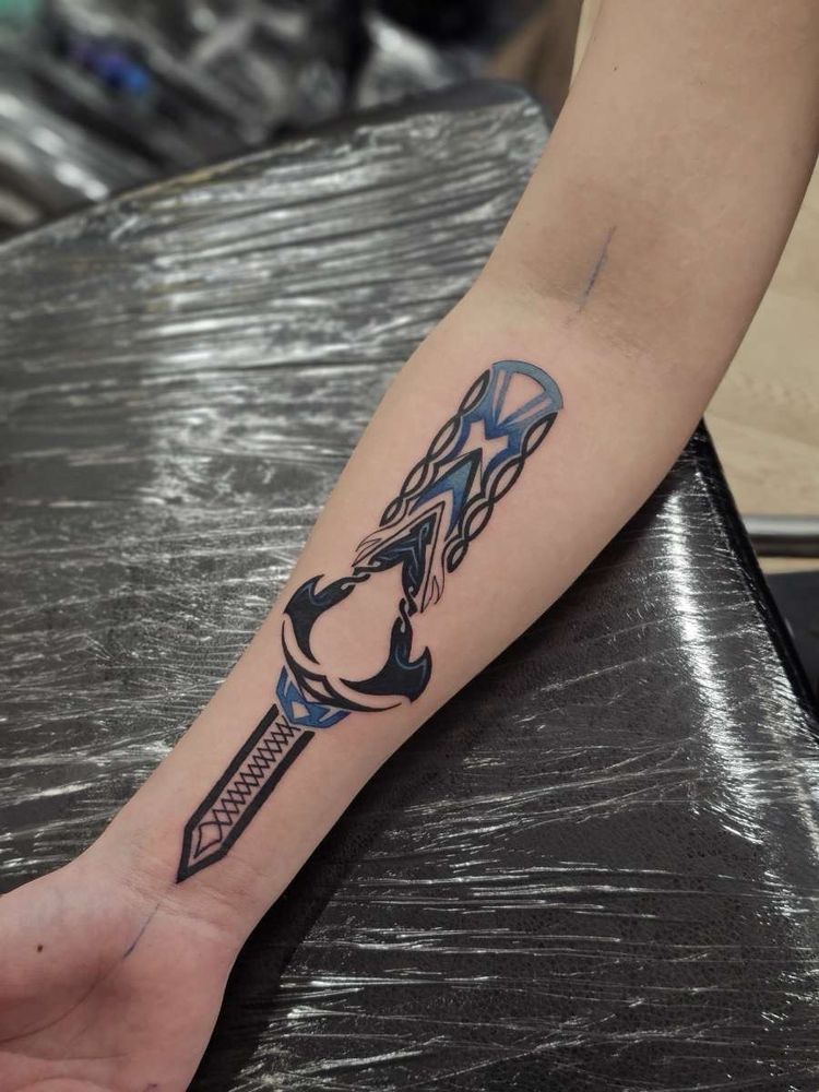 A tattoo on the inside of Alberto’s forearm. It mimics the idea of a hidden blade from assassin’s creed, with the symbol from the Valhalla version of the game visible on it. 