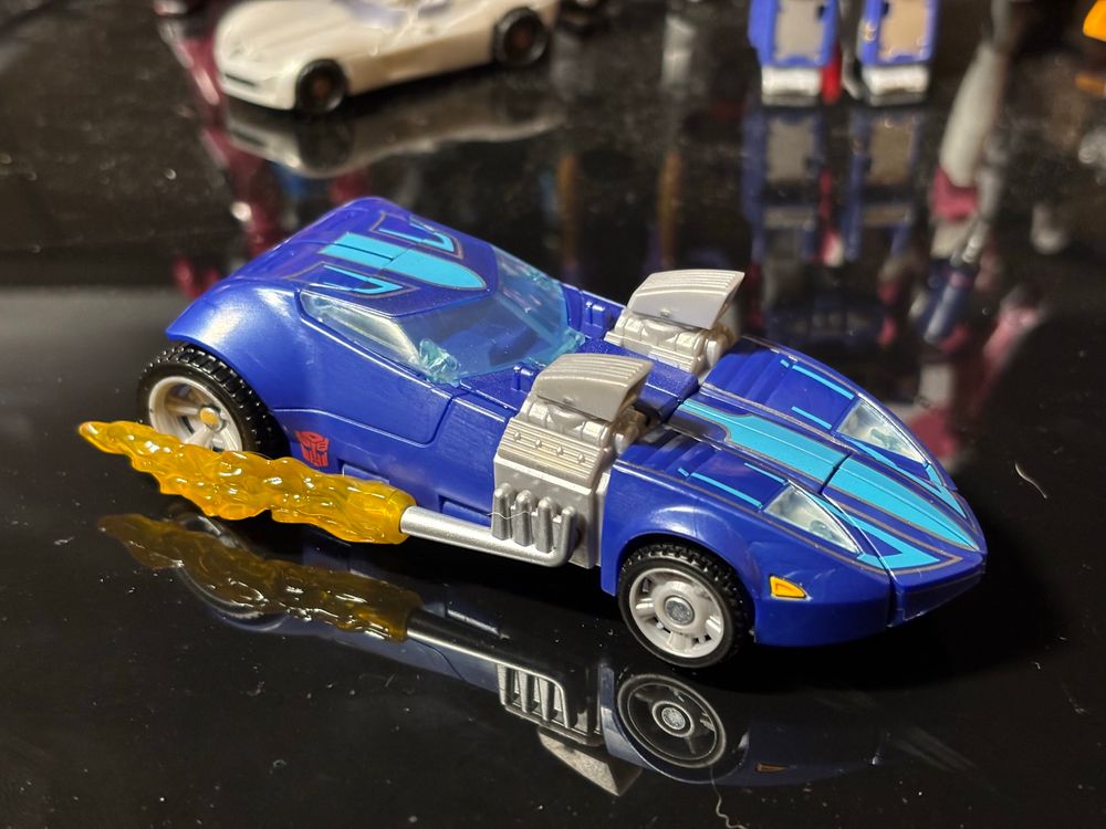 Transformers Autobot Twin Mill (Hot Wheels Collaboration) in vehicle mode. The blue car is a made-up futuristic hot rod design with a pointed hood and two large air intakes connected to side-mounted exhaust pipes that shoot removable flames.
