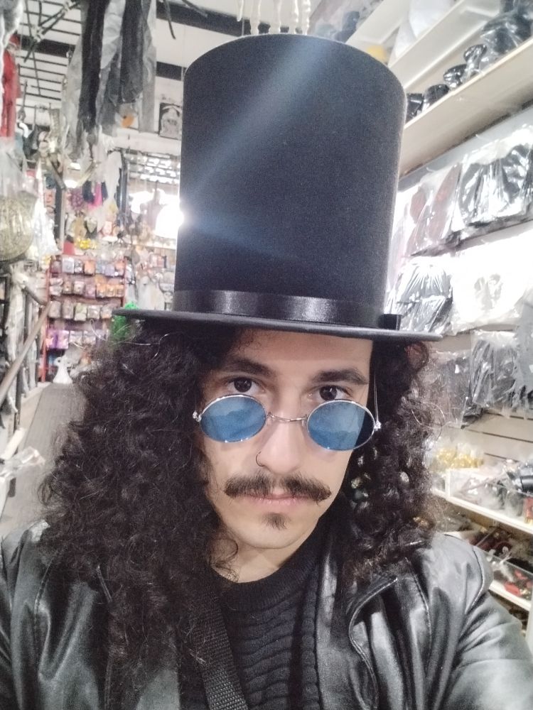 Peralta vestido com uma cartola e  óculos redondos de lente azul