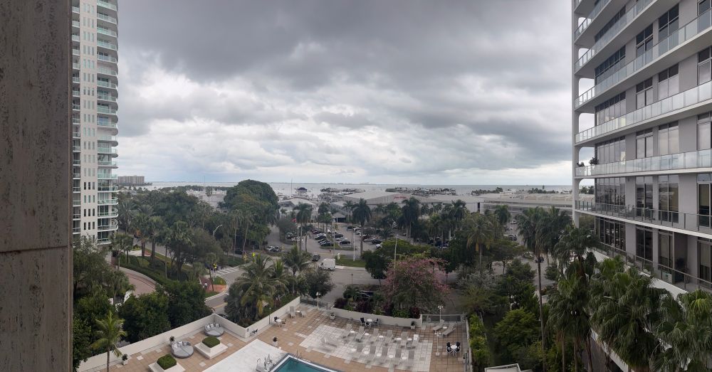 Panoramic view from a balcony in Coconut Grove with a view of the water and a marina.  The sky is mostly cloudy.