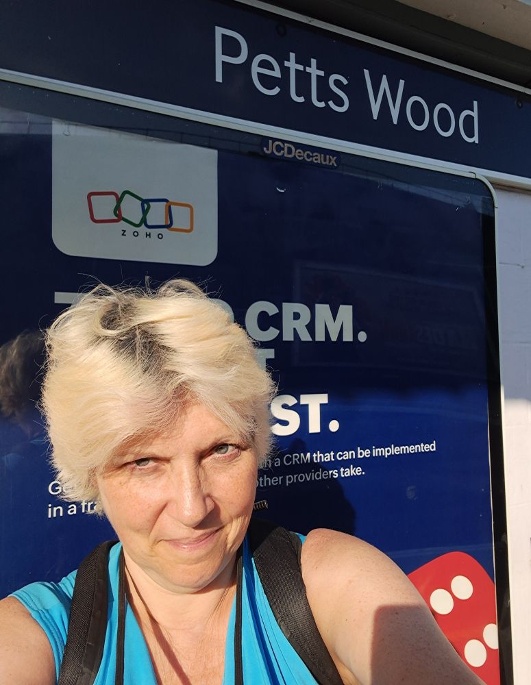 A woman in front of a train station sign that says Petts Wood
