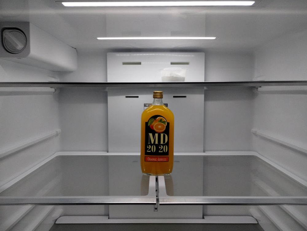 A bottle of Mad Dog 20/20 Orange Jubilee in an otherwise empty fridge. 