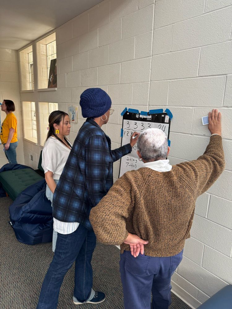 Three people working on a vertical non permanent surface.