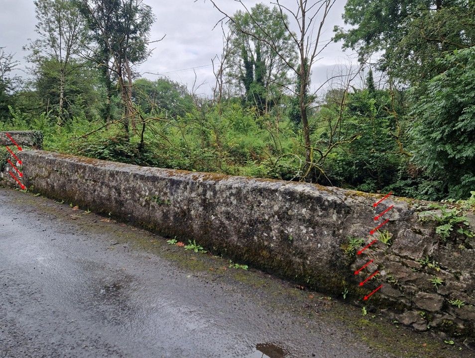 A bridge with repairs in concrete marked out with red arrows