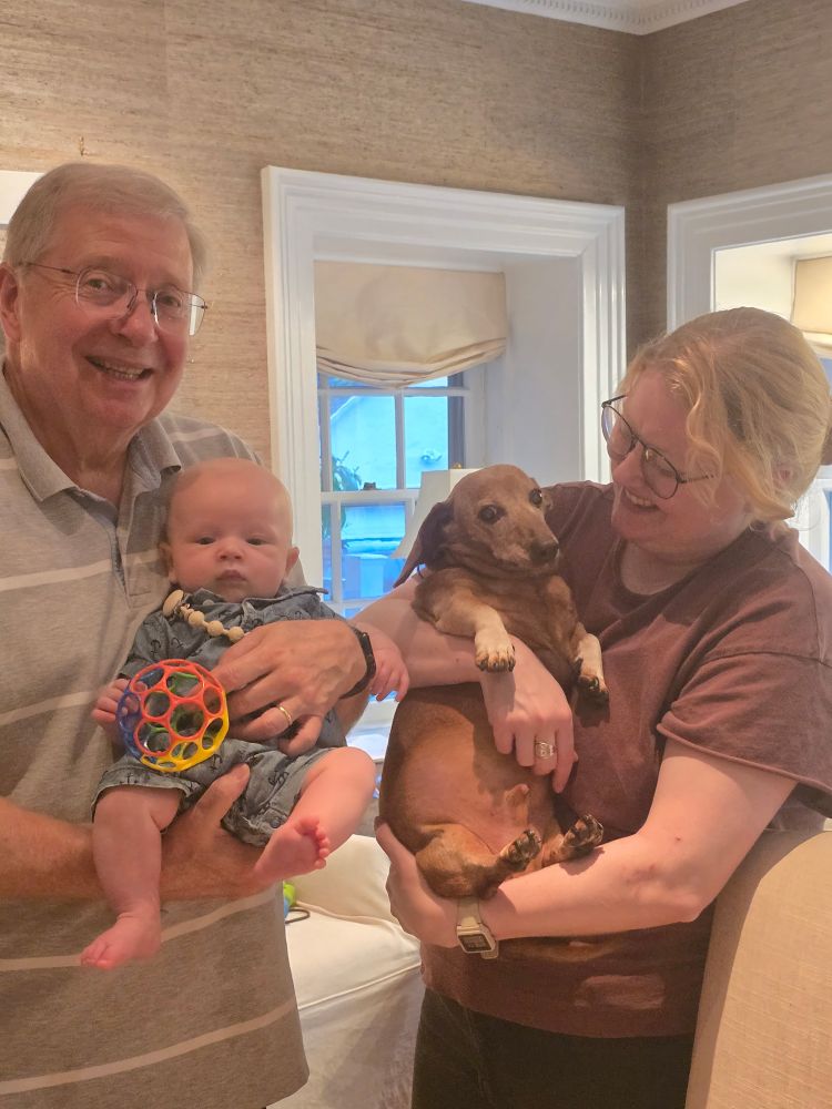 My dad holding my 3-month old nephew, and my sister holding Pretzel The dachshund