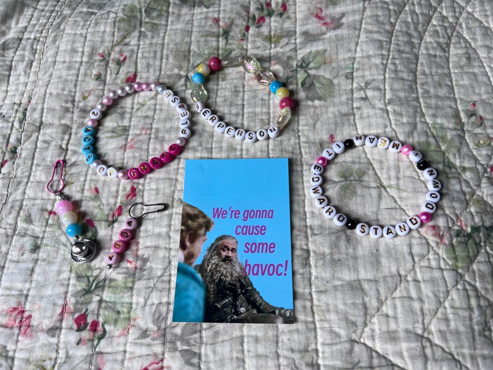 3 hand made bracelets and 2 adorable zipper pulls, as well as a sweet little card that says “we’re gonna cause some havoc!”

The bracelets read:
MERPERSON
2 ACTS OF GRACE PLEASE
I MEAN IT EDWARD STAND DOWN