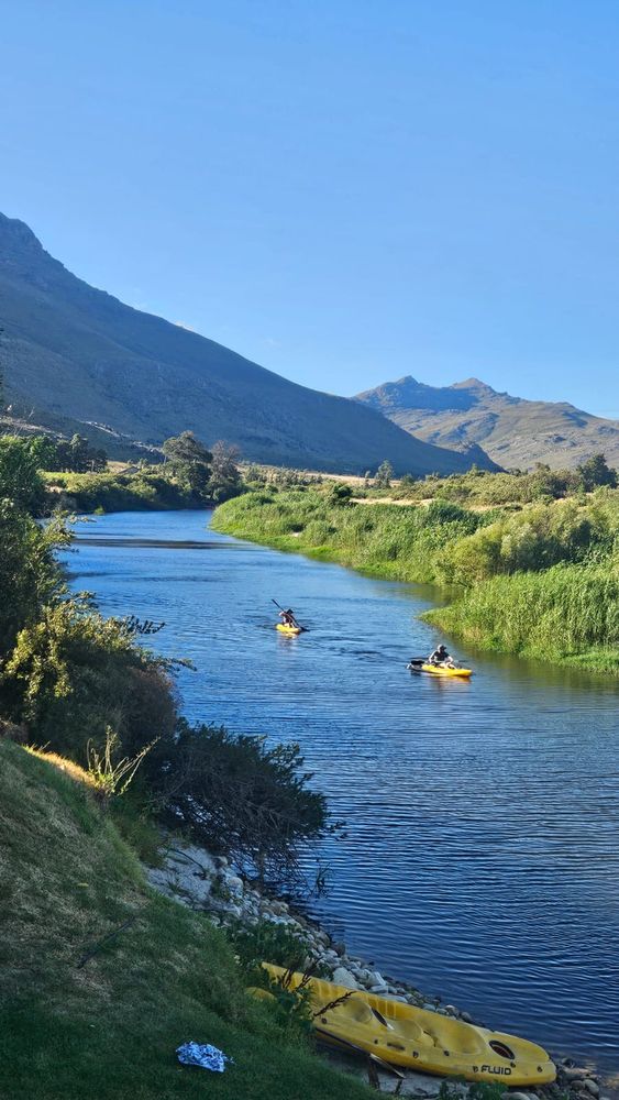 Two yellow kayaks paddling leisurely down a river in the picturesque countryside. One of them is me. 