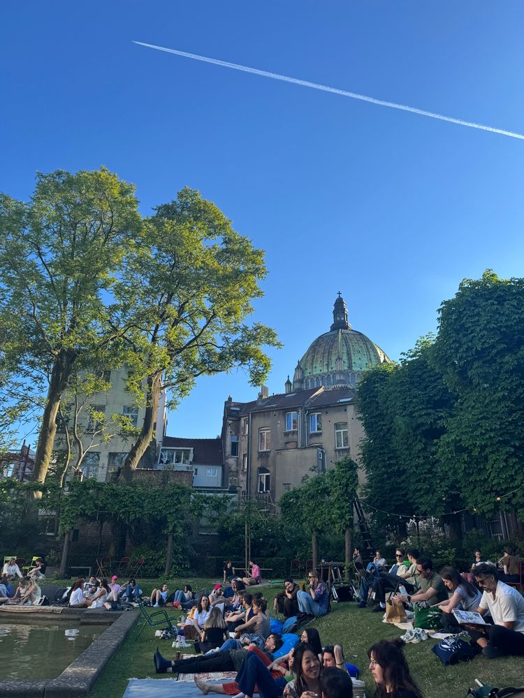 image of an urban garden in brussels with people sitting around on the grass 