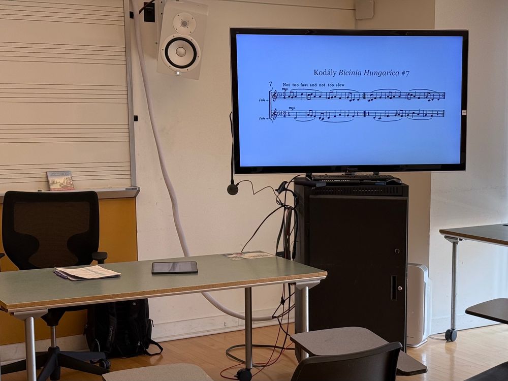 Music classroom with selection from Kodály's BICINIA HUNGARICA on the monitor. The tempo marking is "Not too fast, and not too slow."