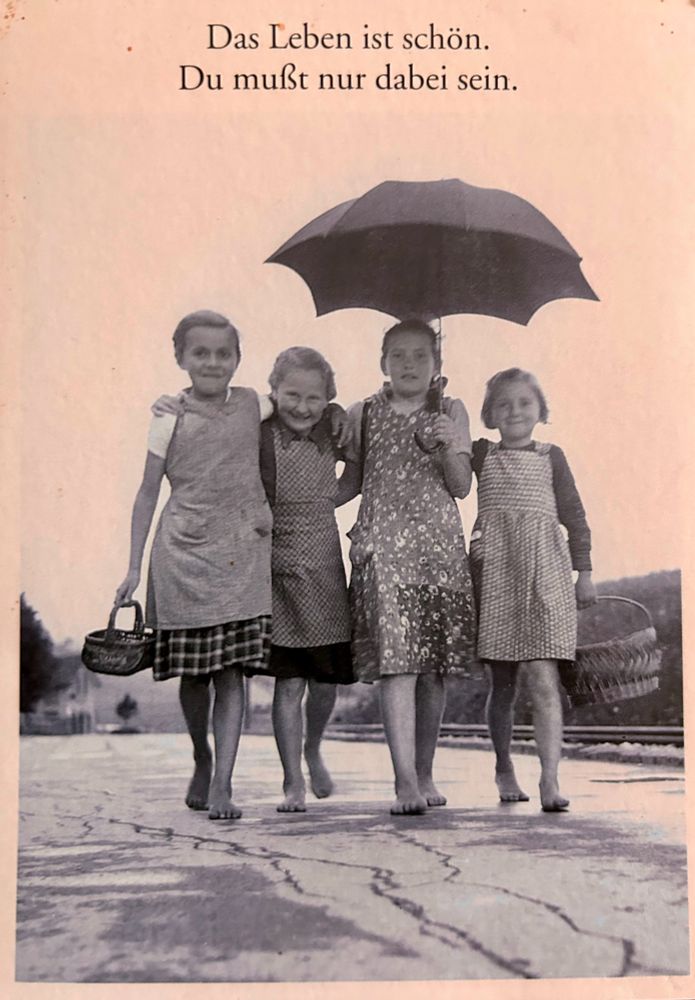 Das Leben ist schön. Du musst nur dabei sein. Das Bild zeigt vier Mädchen in Schürzen, die glücklich des Weges geben.