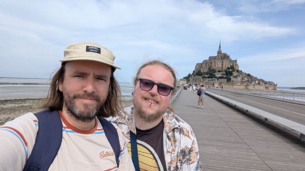 A selfie of Me and Robbie on a boardwalk with Mont Saint-Michel in the background