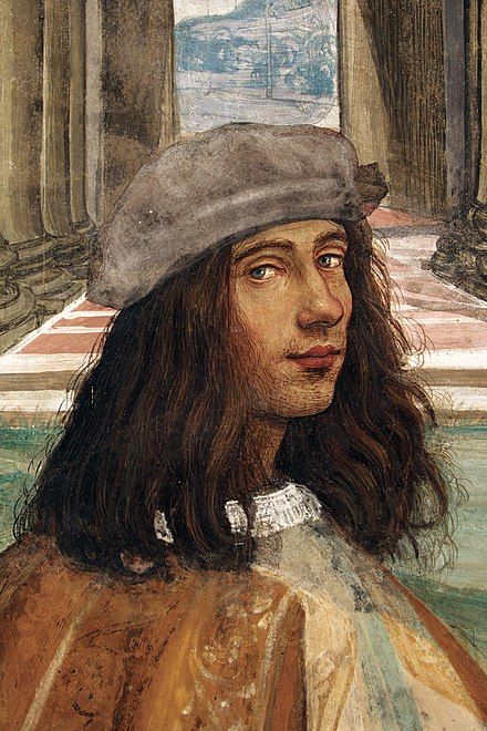 Detail of a painting of a young man. He is looking at the viewer sideways, with an slightly upturned mouth indicating a wry smile. He has shoulder-length wavy dark brown hair, blue eyes and wears and grey cap and brown smock. 