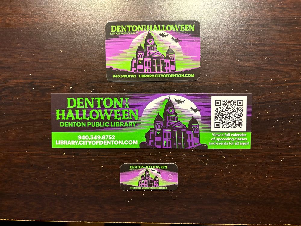 Library card, bookmark, and keychain card with the old courthouse on the square bathed in purple and green and surrounded by bats.