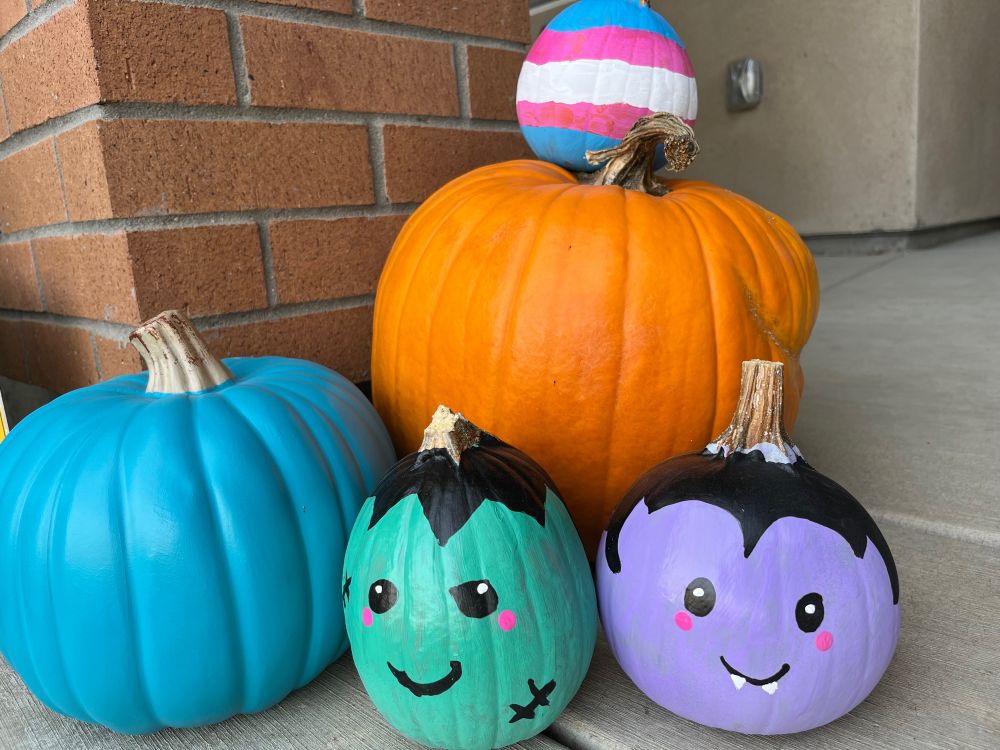 4 pumpkins- 1 teal , 1 orange, 1 painted cartoon Frankenstein, 1 painted vampire, 1 painted trans flag stripes