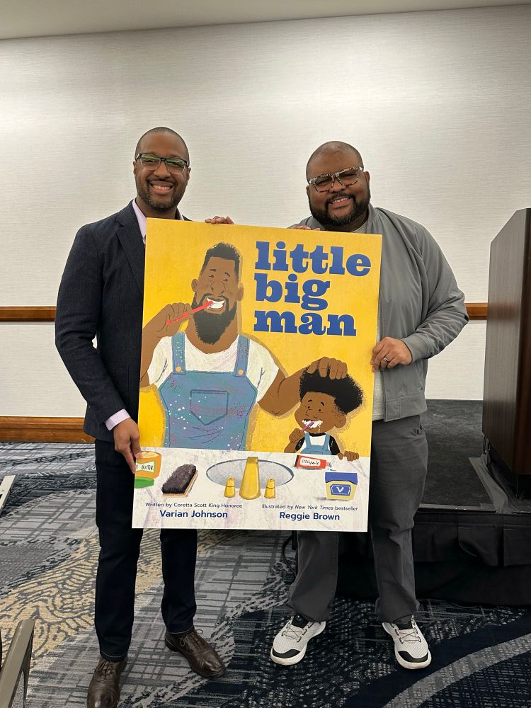 Varian Johnson and Reggie Brown hold a poster of their upcoming picture book, LITTLE BIG MAN, published by Scholastic
