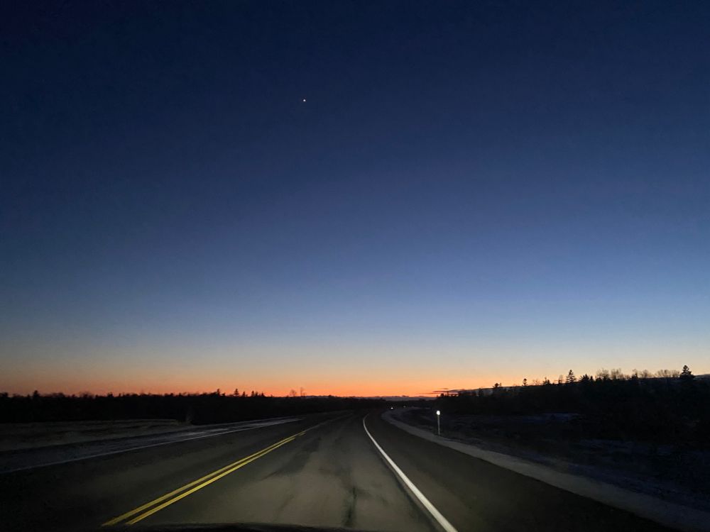 ciel dégagé entre chien et loup. 
route pavée disparaissant au tiers inférieur dans la noirceur de l’horizon. La lueur d’un soleil déjà loin adoucit l’orangé qui découpe l’horizon en se dégradant vers les astres à de l’indigo, lequel est percé tout en haut du fin scintillement d’une étoile. 