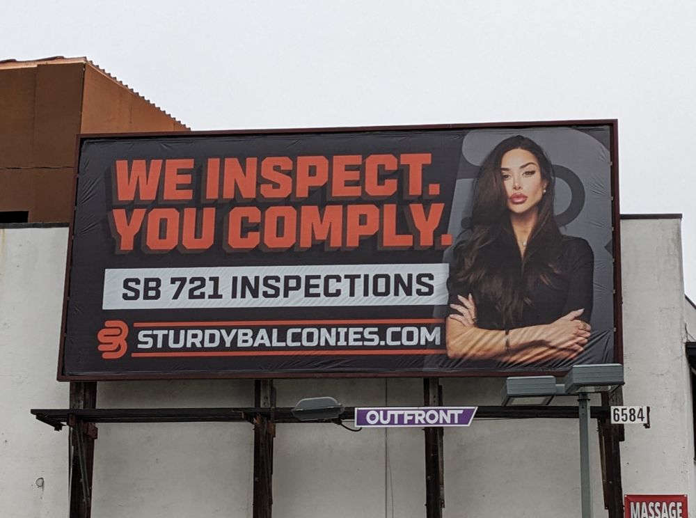 Billboard with a severe looking woman and text "We inspect. You comply."