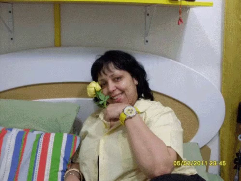 a woman is holding a yellow rose in her mouth and a photo was taken on 05/02/2011