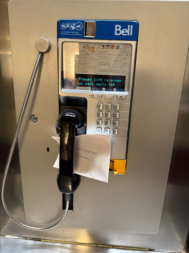 A payphone with an envelope wedged under the receiver 