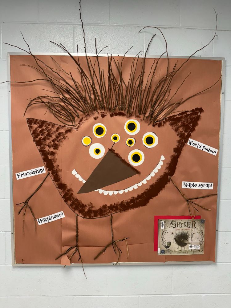A bulletin board with the character “Stickler” made from paint and found sticks 
