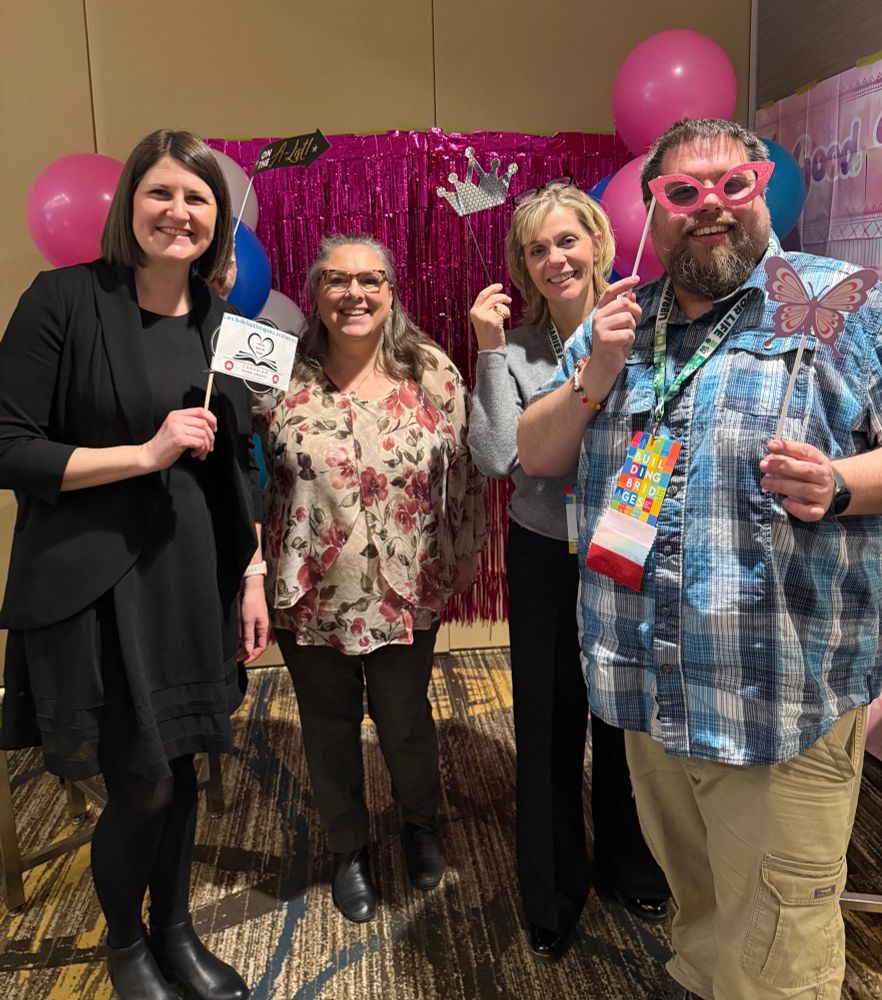 District Level Teacher Librarians from British Columbia in a group photo. They are holding funny signs and props. 