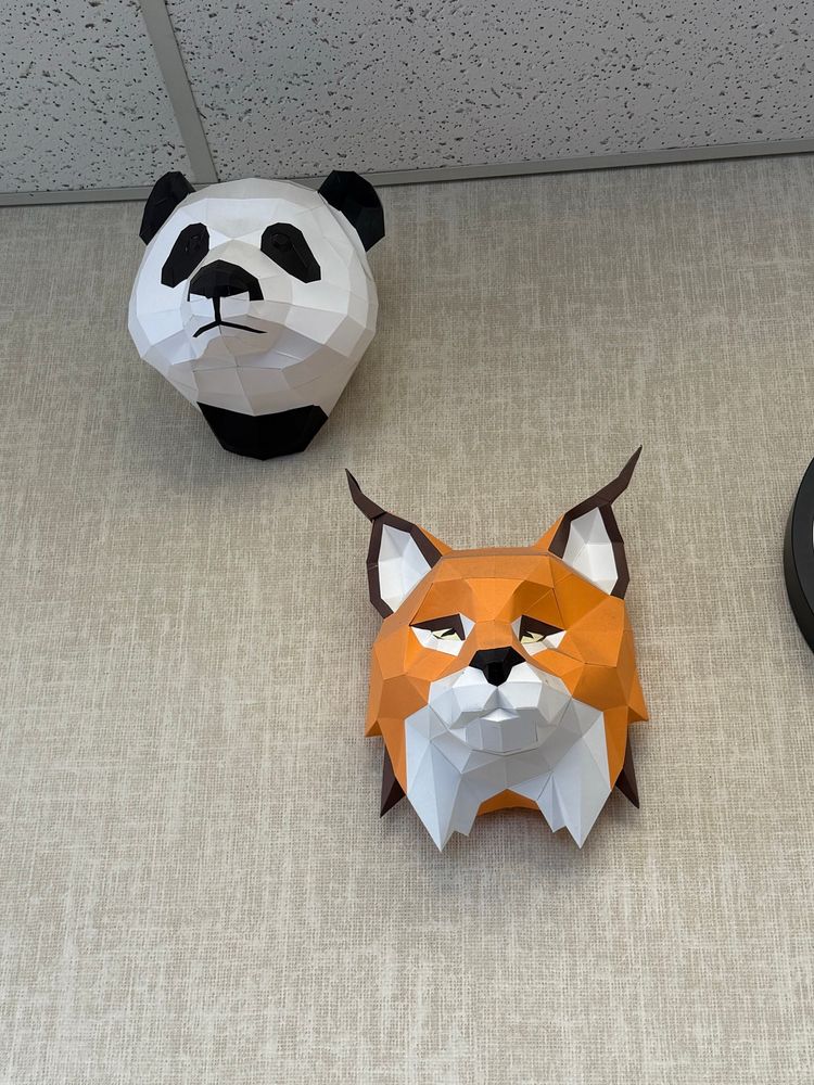 Handmade animal heads hanging on the wall made from folded paper. There is a panda and a red fox
