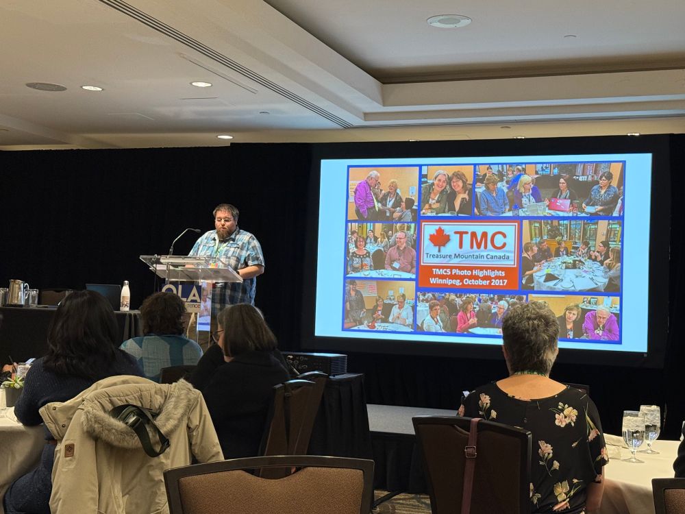 Joseph Jeffery, Canadian School Libraries Chair speaking at a lectern in front of a slide that says “TMC”