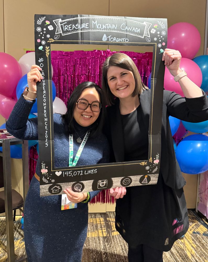 Two Teacher Librarians from Surrey in a group photo. They are holding a large cardboard photo frame that says Treasure Mountain Canada Toronto