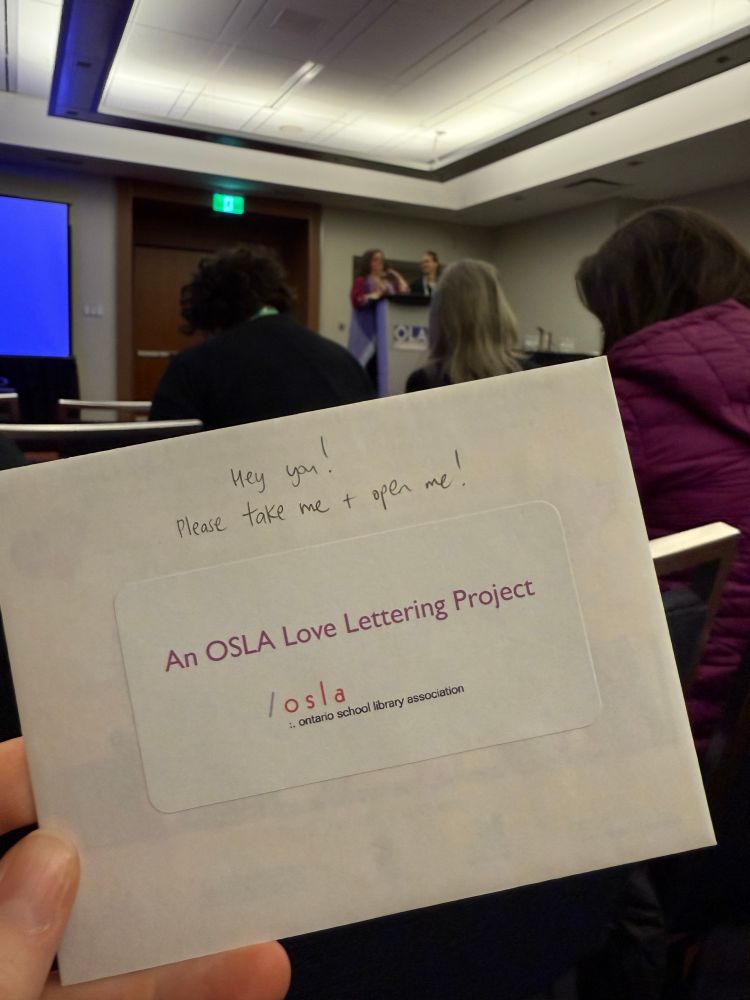 An envelope that says “An OSLA Love Lettering Project” and “Hey you! Please take me + open me!”