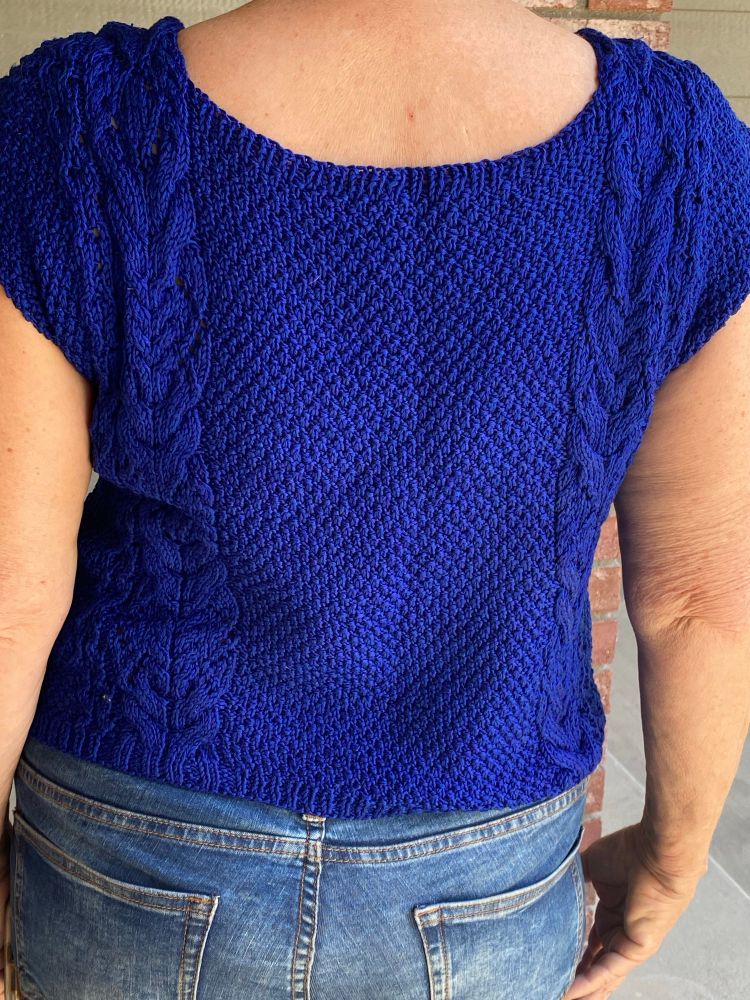 A Bluesky knitted garment with moss stitch and bands of cables on either side. This is the back  view