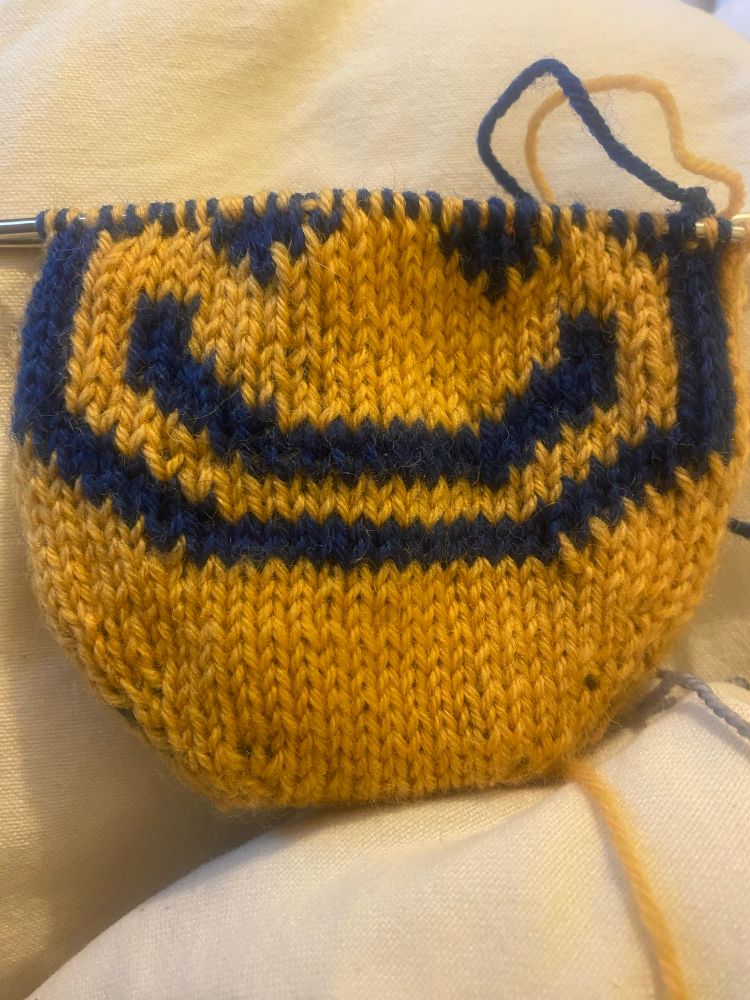 A toe up sock, yellow with blue showing double knitting 